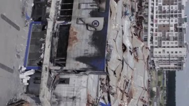 This stock vertical video shows a destroyed building of a shopping center in Bucha during the war in Ukraine, grey, flat video