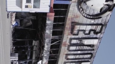 This stock vertical video shows a destroyed building of a shopping center in Bucha during the war in Ukraine, grey, flat video