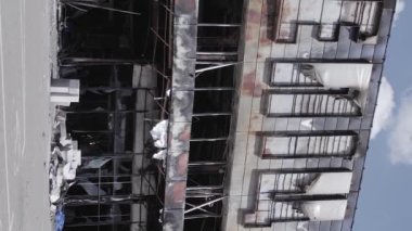 This stock vertical video shows a destroyed building of a shopping center in Bucha during the war in Ukraine, grey, flat video