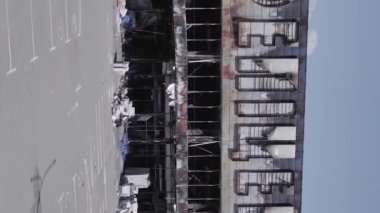 This stock vertical video shows a destroyed building of a shopping center in Bucha during the war in Ukraine, grey, flat video