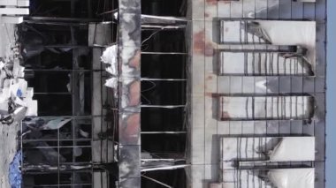 This stock vertical video shows a destroyed building of a shopping center in Bucha during the war in Ukraine, grey, flat video