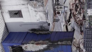This stock vertical video shows a destroyed building of a shopping center in Bucha during the war in Ukraine, grey, flat video