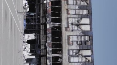This stock vertical video shows a destroyed building of a shopping center in Bucha during the war in Ukraine, grey, flat video