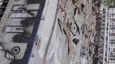 This stock vertical video shows a destroyed building of a shopping center in Bucha during the war in Ukraine, grey, flat video