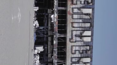 This stock vertical video shows a destroyed building of a shopping center in Bucha during the war in Ukraine, grey, flat video