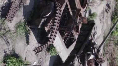 This stock vertical video shows an aerial view of destroyed military equipment in Ukraine, flat, grey video
