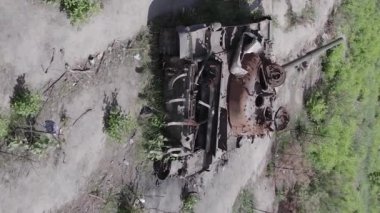 This stock vertical video shows an aerial view of destroyed military equipment in Ukraine, flat, grey video