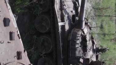 This stock vertical video shows an aerial view of destroyed military equipment in Ukraine, flat, grey video