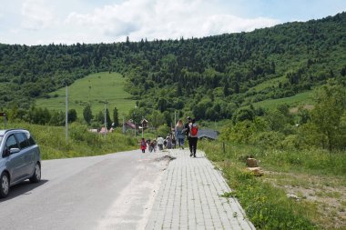 People walk along the road in the Carpathian mountains.  