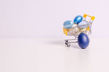 Easter colored eggs in a shopping cart on a white background clipart