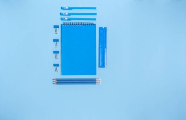 Exercise book with items for school on a blue background. Concept of preparation for school, stationery. Flat lay, top view.