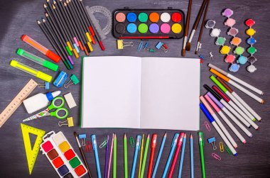 Metin için yeri olan bir defter ve yaratıcılık için çeşitli kırtasiye aksesuarları siyah bir arkaplanda. Okul hazırlık konsepti, düz yatak, fotokopi alanı. Yukarıdan görüntüle.