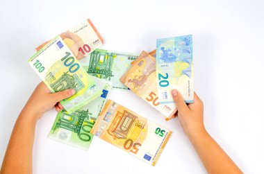 Different euro banknotes in children's hands on a white table. The concept of money, economy, finance, savings. Close-up