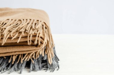 Beyaz arka planda yün eşarplardan yapılmış sıcak sonbahar eşarpları yığılmış. Sıcaklık ve rahatlık kavramı. Yakın plan..