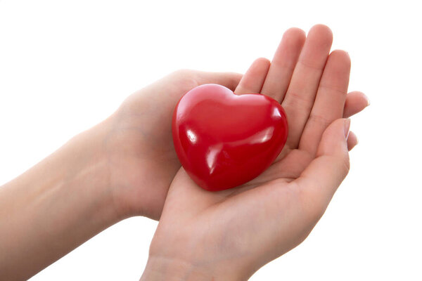 Female hand holding a cut out paper heart. Isolated on a white background.