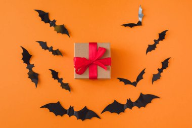 Turuncu arkaplandaki yarasaların arka planında bir hediye. Boşluğu kopyala