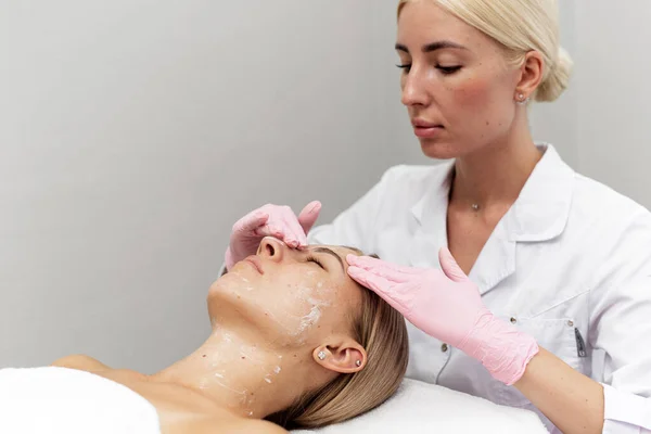 Kobieta kosmetyczka czyści i nawilża skórę pacjentów w salonie spa — Zdjęcie stockowe