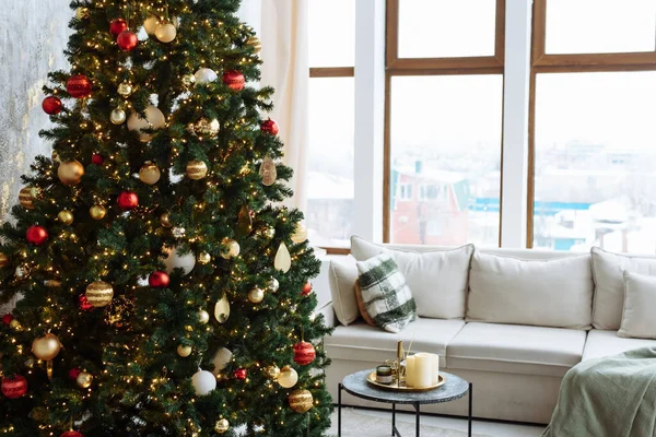 Albero di Natale con palline rosse e d'oro e ghirlanda d'oro luci in una stanza luminosa. — Foto Stock