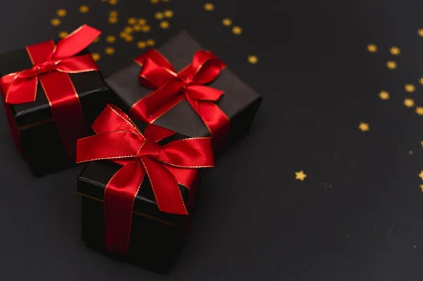 Gyönyörű karácsonyi arany hópelyhek ajándékokkal egy sötét fekete háttér. Lapos fekvés. Fénymásolási hely. — Stock Fotó
