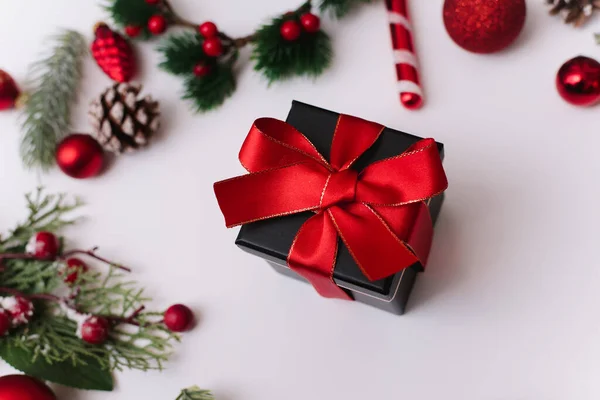 Composición de Año Nuevo o Navidad sobre un fondo blanco con una caja de regalo, con una cinta roja con ramas de abeto, juguetes, espacio de copia para felicitaciones —  Fotos de Stock