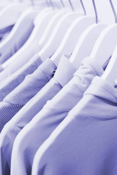 Clothes on hangers and display cases in purple colors of 2022. Turtlenecks, T-shirts, sweaters, sweatshirts in a very peri color. — Stok fotoğraf