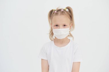Portrait of a little girl in a medical protective mask to prevent infection, illness, flu or covid-19, copy space, white studio background. Health care concept