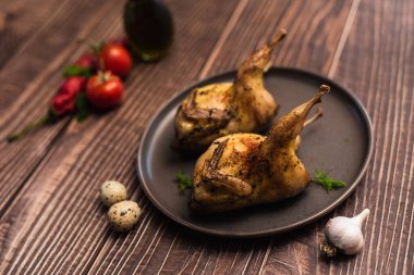 Tabakta tam pişmiş bıldırcın. Domatesli bıldırcın, sarımsak ve bıldırcın yumurtası..