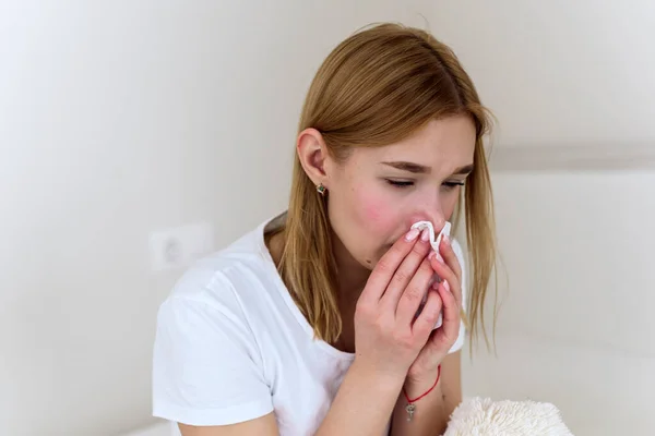 Mulher milenar doente sentindo-se mal, luta fraca contra a gripe, corrimento nasal, descanso em casa, conceito de problema de saúde. A mulher sopra o nariz num lenço. depressão, tristeza e choro — Fotografia de Stock