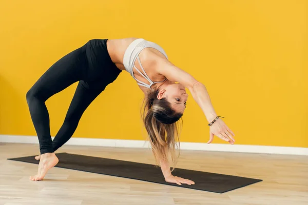 Yogini utövar yoga poserar i gymmet. Kvinnan står upp och ner — Stockfoto