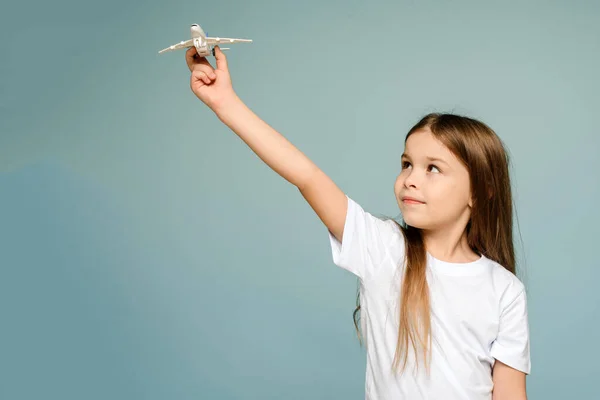 Foto de una niña feliz sosteniendo un avión de juguete. Espacio de copia aislado sobre fondo de color azul — Foto de Stock