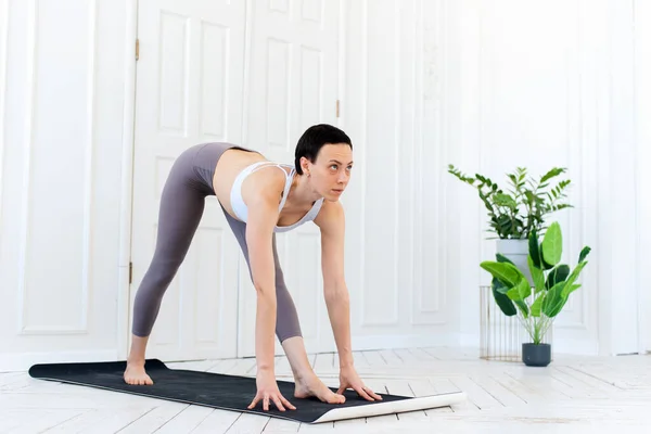 Ung kvinna som utövar yoga i en ljus bakgrund. Friska livsstil koncept — Stockfoto