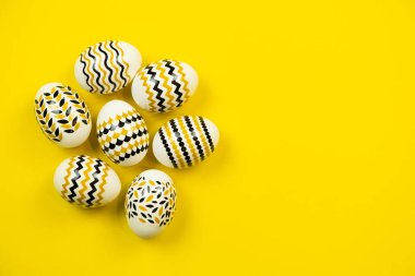 Sarı arka planda altın, siyah, beyaz yumurtalar. Yukarıdan bak. Metin için kopyalama alanı olan Paskalya kartı.