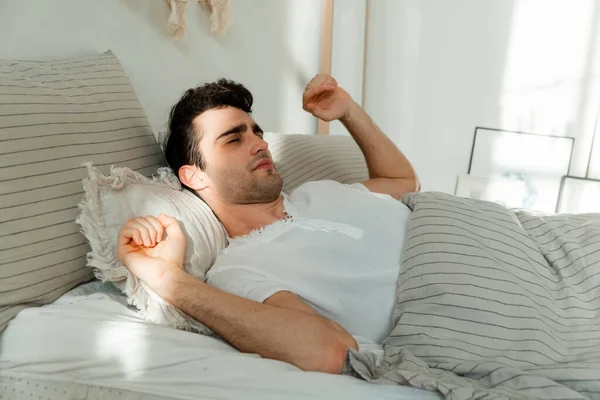 A young man wakes up from the first ray of the sun. — Stock Photo, Image