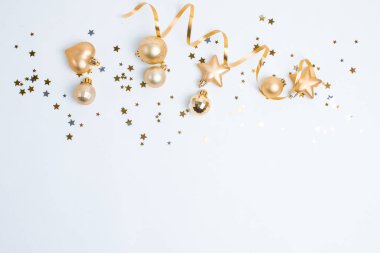 Beyaz arka planda altın oyuncaklar ve kurdelelerin Noel kompozisyonu