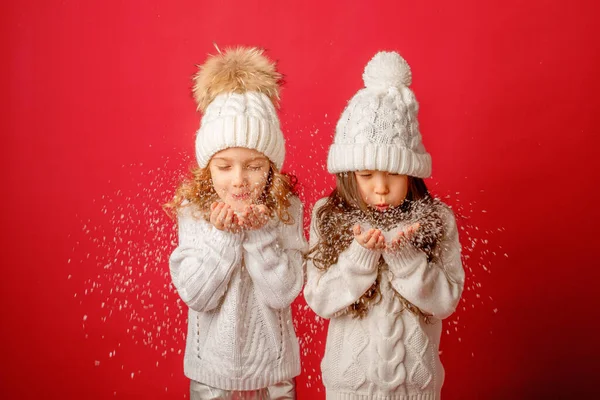 Kleine Mädchen Die Schnee Auf Rotem Hintergrund Pusten lizenzfreie Stockbilder