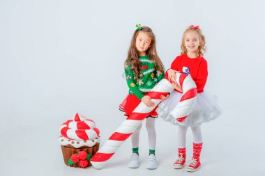 İki küçük kız kek ve büyük karamelli beyaz arka planda izole edilmiş.