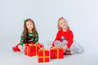 Noel hediyeleri taşıyan iki küçük kız beyaz bir arka planda izole edilmiş.
