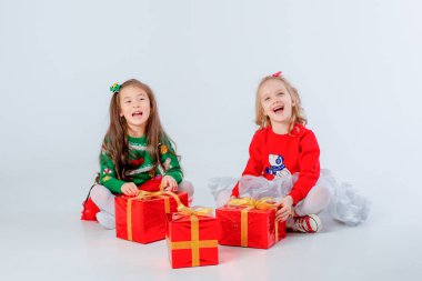 Noel hediyeleri taşıyan iki küçük kız beyaz bir arka planda izole edilmiş.