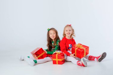 Noel hediyeleri taşıyan iki küçük kız beyaz bir arka planda izole edilmiş.