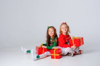 Noel hediyeleri taşıyan iki küçük kız beyaz bir arka planda izole edilmiş.