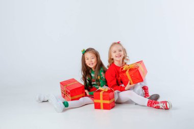 Noel hediyeleri taşıyan iki küçük kız beyaz bir arka planda izole edilmiş.