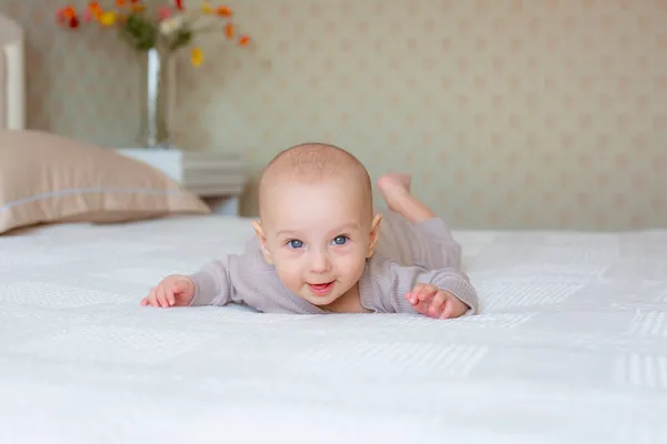 Baby Liegt Auf Dem Bett Schlafzimmer Auf Dem Bauch lizenzfreie Stockbilder
