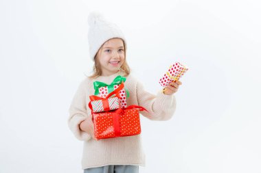 Beyaz arka planda izole edilmiş hediye kutularıyla kışlık şapkalı şirin küçük çocuk.