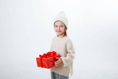 Beyaz arka planda izole edilmiş hediye kutularıyla kışlık şapkalı şirin küçük çocuk.