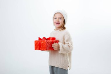 Beyaz arka planda izole edilmiş hediye kutularıyla kışlık şapkalı şirin küçük çocuk.