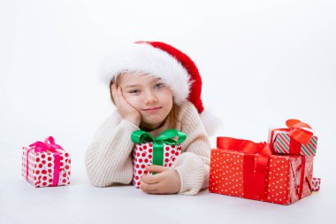 Noel Baba şapkalı şirin bir çocuk. Beyaz arka planda kutular dolusu hediyeler var.