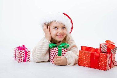 Noel Baba şapkalı şirin bir çocuk. Beyaz arka planda kutular dolusu hediyeler var.