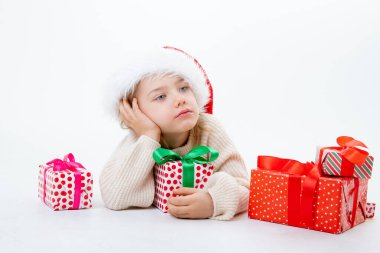 Noel Baba şapkalı şirin bir çocuk. Beyaz arka planda kutular dolusu hediyeler var.