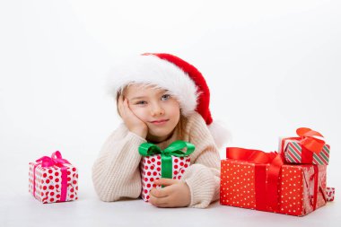 Noel Baba şapkalı şirin bir çocuk. Beyaz arka planda kutular dolusu hediyeler var.