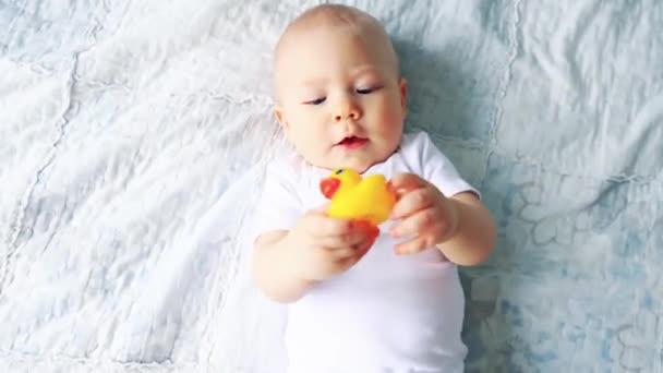 赤ちゃん男の子遊びますとともにおもちゃベッドの上のビューに横たわっている — ストック動画